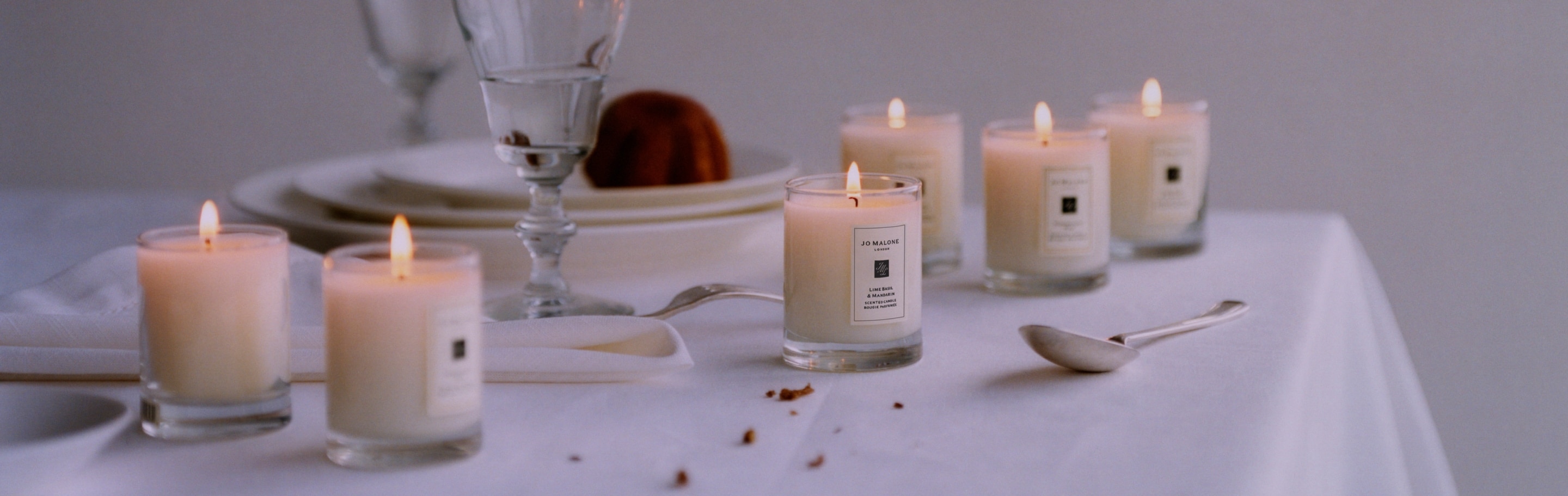 six travel sized candles scattered across a dining table